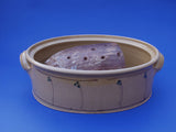 Ein weiteres Bild des gelben ovalen Keramik Brottopfes mit einem rustikalen Brotleib zum Größenvergleich.